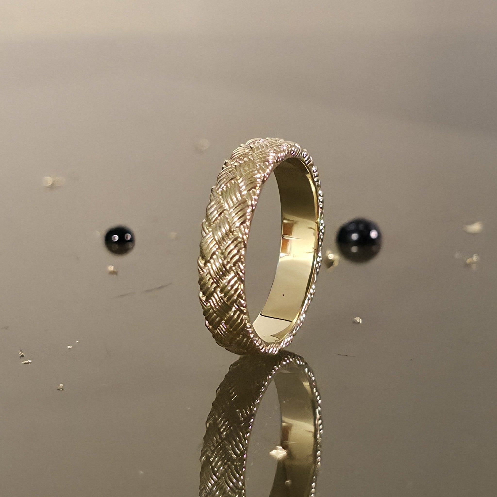 Handcrafted woven gold wedding ring photographed on black background