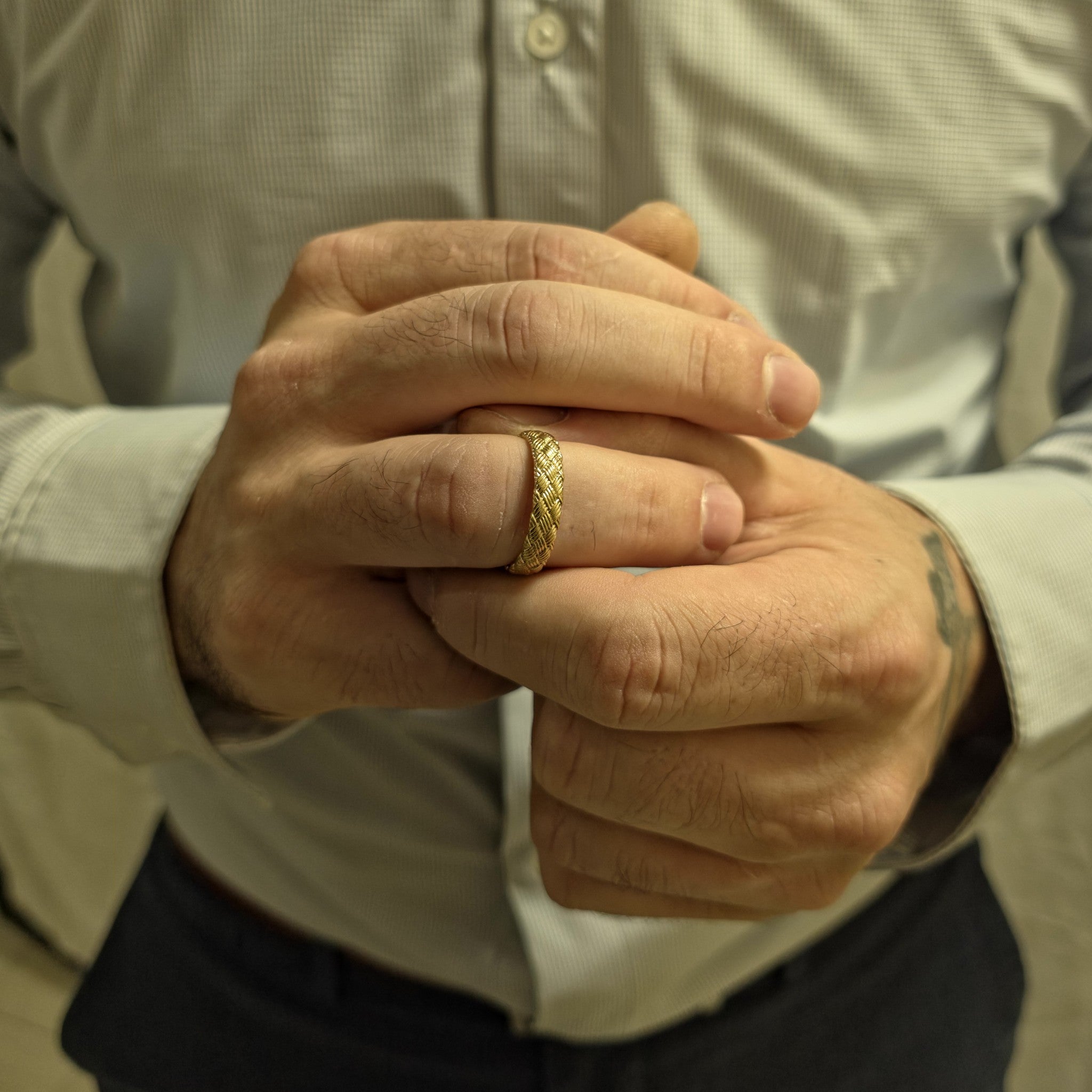 Woven gold ring on a man’s hand showing exterior
