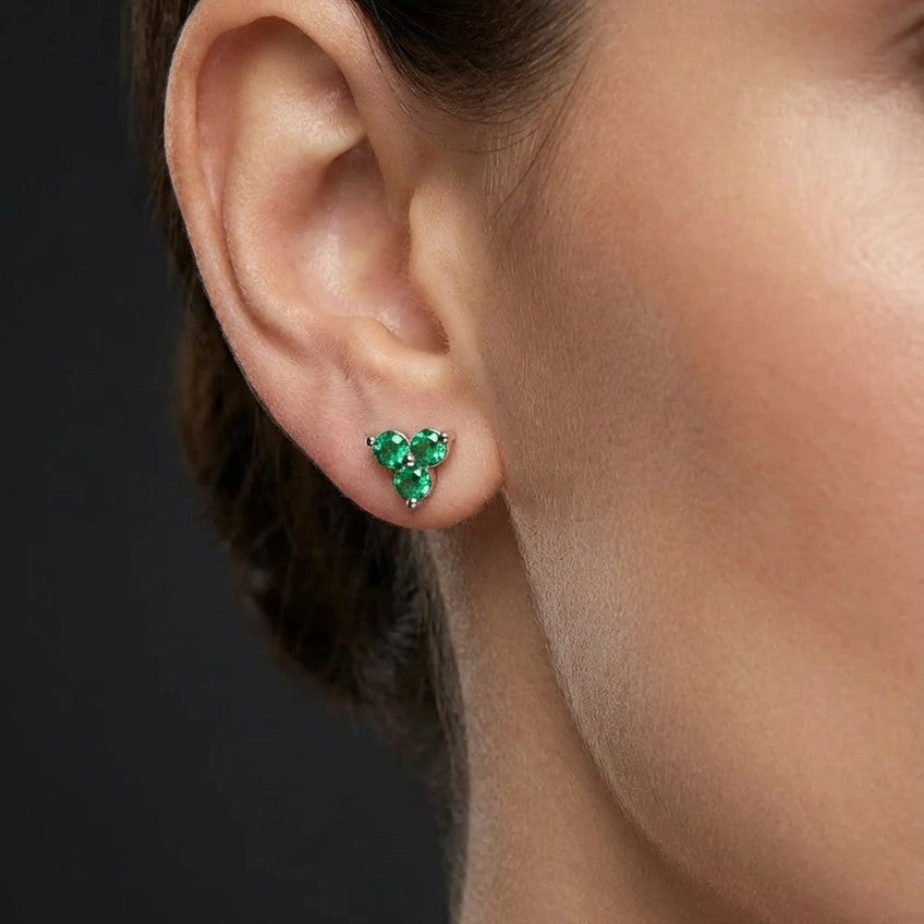 Woman wearing Zirelle emerald triad stud earrings with three stone cluster design in green gemstones